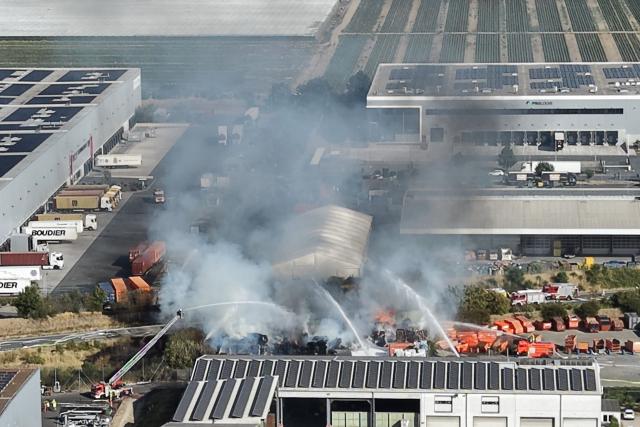 06 August 2026, Hesse, Gernsheim: Firefighters extinguish a fire at a waste management facility in Gernsheim. According to police, pallets and trash are burning on the premises. Photo: Marc Schüler/dpa