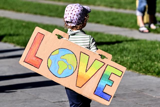 06 August 2026, Berlin: A young boy holds up a sign that reads "Love" during a demonstration by the climate movement "Fridays for Future." Photo: Britta Pedersen/dpa - ATTENTION: editorial use only in connection with the latest coverage and only if the credit mentioned above is referenced in full