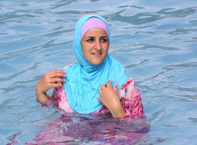 FILED - 20 August 2012, Berlin: FILE PHOTO - A young Turkish woman cools off while wearing a burkini at an open-air pool in Berlin. Photo: picture alliance / dpa