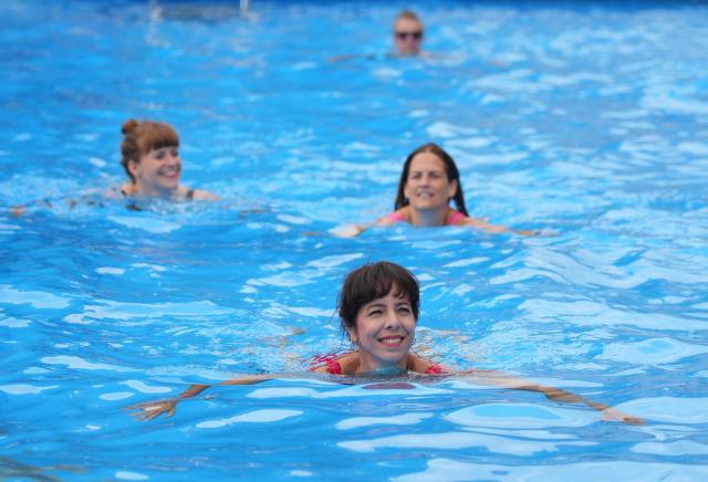 07 August 2026, Berlin: Elif Eralp (front), the Left Party's top candidate for the Berlin House of Representatives election, swims in the public pool in front of the Volksbuehne at Rosa-Luxemburg-Platz. The new artistic director, Lilienthal, also opens the theatre season with "Volksbad". The pool is scheduled to remain open through October. Photo: Soeren Stache/dpa
