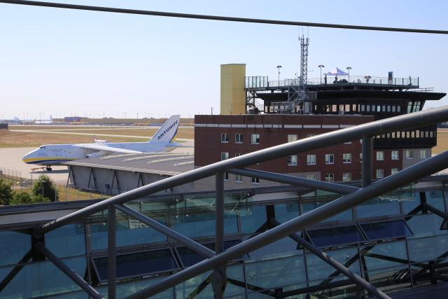 08 August 2026, Saxony, Schkeuditz: A Ukrainian Antonov aircraft is parked at Leipzig/Halle Airport. The old control tower building, which was previously used as an observation deck, is visible in the foreground on the right. Investigations are underway following a drone incident early Wednesday morning. According to security sources, a drone equipped for an attack was seized near a Ukrainian transport aircraft. Security authorities remain on high alert. Photo: Tobias Junghannß/dpa