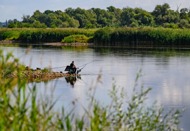 08 August 2026, Brandenburg, Frankfurt (Oder): An angler sits on a groyne along the Oder River. The ongoing drought is having a noticeable impact along the German-Polish border. In Frankfurt (Oder), the water level of the border river has fallen to just 88 centimetres. Photo: Patrick Pleul/dpa