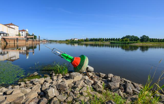 08 August 2026, Brandenburg, Frankfurt (Oder): A navigation marker lies stranded on dry land along the Oder River. Green and red navigation buoys, which normally float on the water, have been left stranded on the rocks of groynes in some places as water levels recede. The ongoing drought is clearly visible along the German-Polish border. In Frankfurt (Oder), the water level of the border river has fallen to just 88 centimetres. Photo: Patrick Pleul/dpa