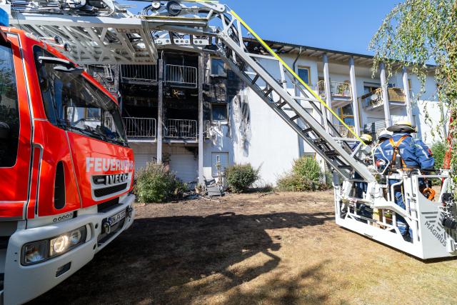 08 August 2026, Bavaria, Rednitzhembach: Emergency responders stand infront of the burned facade of a senior living facility, after a fire broke out. The residents were evacuated. Photo: Pia Bayer/dpa