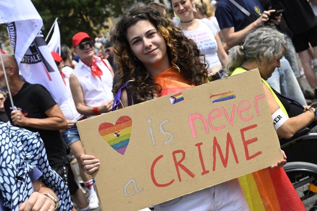 09 August 2026, North Rhine-Westphalia, Cologne: A person holds up a sign that reads "is never a crime" during the solidarity march-held under the slogan "Cologne Shows Solidarity, Cologne Takes a Stand". Several queer initiatives and organizations had called for the march following the Islamist attack on the outskirts of Berlin's CSD. Photo: Roberto Pfeil/dpa