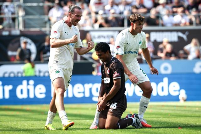 09 August 2026, Hamburg: Greuther's Jannis Heuer (L) and Lukas Reich celebrate a goal next to St. Pauli's Joel Chima Fujita during the German 2nd Bundesliga soccer match between FC St. Pauli and SpVgg Greuther Fuerth at Millerntor Stadium. Photo: Christian Charisius/dpa - WICHTIGER HINWEIS: Gemäß den Vorgaben der Bundesliga bzw. des DFB Deutscher Fußball-Bund ist es untersagt, in dem Stadion und/oder vom Spiel angefertigte Fotoaufnahmen in Form von Sequenzbildern und/oder videoähnlichen Fotostrecken zu verwerten bzw. verwerten zu lassen.