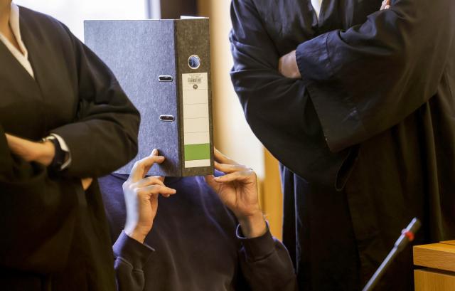 FILED - 05 November 2025, Nordrhein-Westfalen, Aachen: The defendant, a male nurse, sits in the courtroom with a file folder covering his face. The Aachen Regional Court has sentenced a nurse to life in prison for the murder of ten patients. Photo: Oliver Berg/dpa