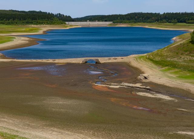 10 August 2026, Saxony, Hartmannsdorf: An aerial view taken by drone shows the historic Zinn Bridge in the Lehnmühle Reservoir in the Eastern Ore Mountains is visible again due to low water levels .The arched bridge of the former Steinbrückmühle settlement in the reservoir is no longer structurally sound, posing a risk of collapse. Photo: Robert Michael/dpa