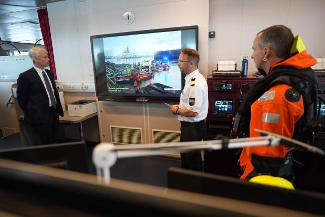 10 August 2026, Schleswig-Holstein, Kiel: Head of the Maritime Rescue Coordination Center in Cuxhaven Commander Robby Renner (C) speaks with German Minister of Transportation Steffen Bilger (L) on the bridge of the multipurpose vessel "Scharhoern" at the Maritime Rescue Coordination Center's command post. During his summer tour, Federal Minister of Transportation Bilger is visiting various projects in northern Germany. Photo: Marcus Brandt/dpa