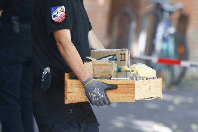 10 August 2026, Schleswig-Holstein, Kiel: An employee of the explosive ordnance disposal unit is carrying items out of a house in Kiel. A private apartment there is currently being searched for suspicious objects. Photo: Frank Molter/dpa