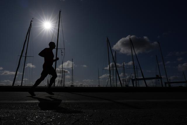 11 August 2026, Schleswig-Holstein, Kiel: A jogger runs past a marina along the Kiellinie in the morning sun. Photo: Marcus Brandt/dpa