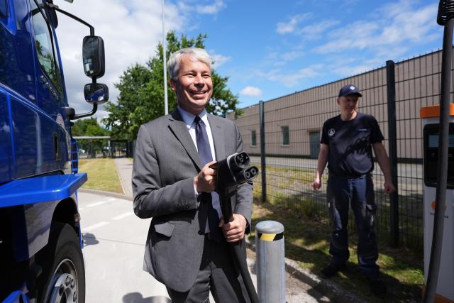 11 August 2026, Schleswig-Holstein, Neumunster: German Transport Minister Steffen Bilger holds up a charging plug during a visit to the Bartels-Langness grocery store location, to learn about a ministry-funded project for publicly accessible charging infrastructure for electric cars and trucks. During his summer tour, Bilger visited various projects in northern Germany. Photo: Marcus Brandt/dpa