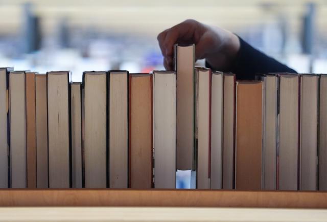 FILED - 19 December 2025, Hamburg: FILE PHOTO - An employee puts a book back on a shelf in the reading room of the Hamburg Central Library at Huehnerposten. Photo: Marcus Brandt/dpa