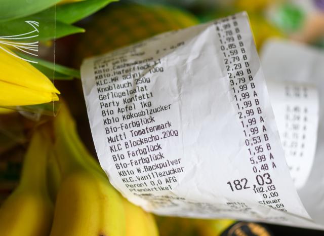 FILED - 09 March 2026, Saxony, Leipzig: FILE PHOTO - A receipt lies on a shopping basket filled with bananas and other groceries. A receipt lies on a full shopping basket. Photo: Hendrik Schmidt/dpa