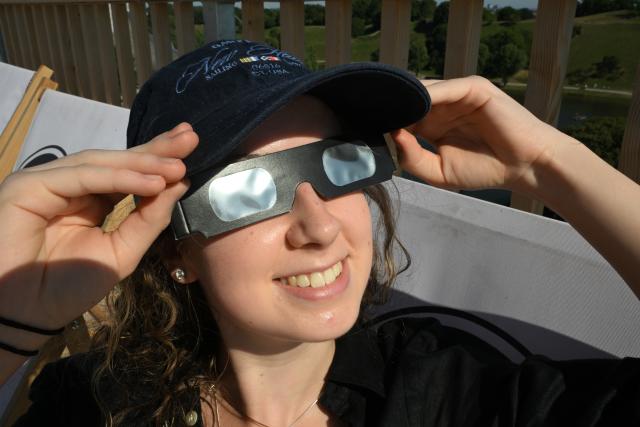 12 August 2026, Bavaria, Munich: Antonia sits in a lounge chair on the SAYAQ Adventure Tower in Munich's Olympic Park, wearing safety goggles, to watch the partial solar eclipse. Photo: Felix Hörhager/dpa