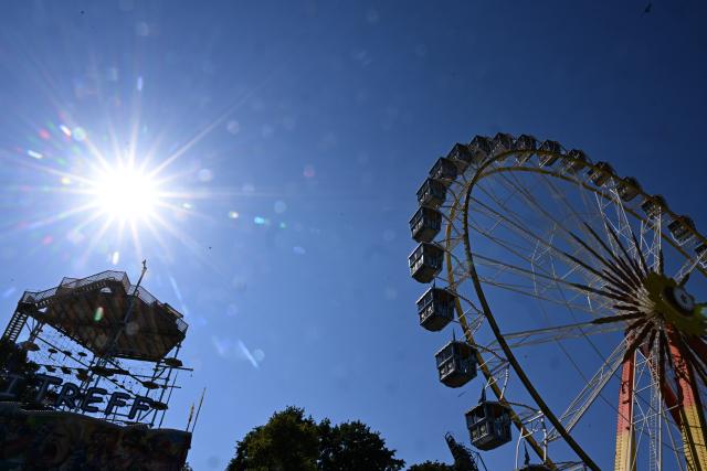 12 August 2026, Bavaria, Munich: The sun is shining over Munich's Olympic Park, a Ferris wheel, and the SAYAQ Adventure Tower ahead of the partial solar eclipse. Photo: Felix Hörhager/dpa