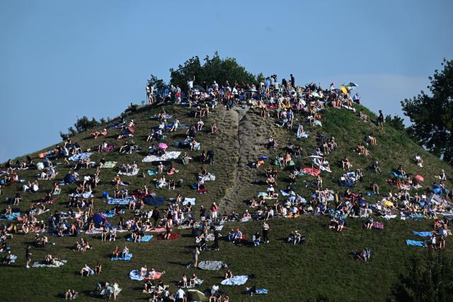 12 August 2026, Bavaria, Munich: Visitors gather on the Olympiaberg in Munich's Olympiapark to watch the partial solar eclipse. Photo: Felix Hörhager/dpa
