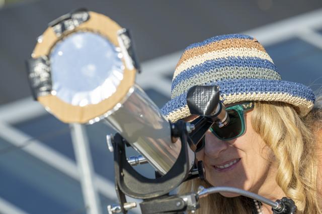 12 August 2026, Bavaria, Munich: An amateur astronomer is setting up her telescope on the rooftop terrace of the Gasteig Cultural Center so she can later observe the partial solar eclipse against the city skyline. Photo: Peter Kneffel/dpa