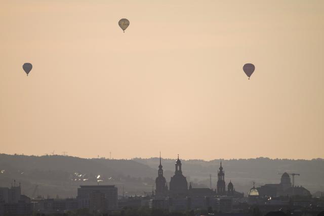 12 August 2026, Saxony, Dresden: Hot-air balloons take off against the backdrop of the historic old town before the start of a partial solar eclipse. Photo: Robert Michael/dpa