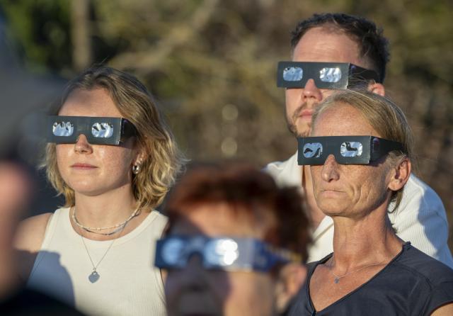 12 August 2026, Bavaria, Munich: Visitors on the rooftop terrace of the Gasteig Cultural Center watch the solar eclipse through special glasses. Photo: Peter Kneffel/dpa