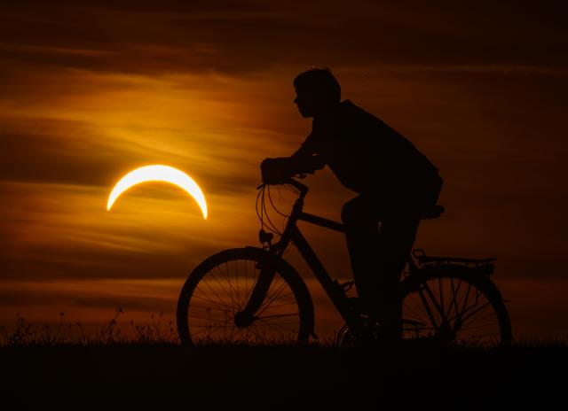 12 August 2026, Brandenburg, Jacobsdorf: A boy on a bicycle watches the partial solar eclipse in eastern Brandenburg. Photo: Patrick Pleul/dpa