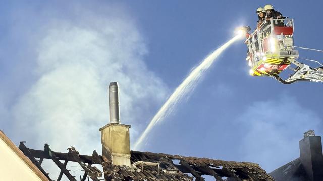 13 August 2026, Hesse, Kelkheim: Firefighters extinguish a fire at a residential building in the Muenster district of the Main-Taunus district. Several people sustained minor injuries in the fire at a single-family home. Photo: Mike Seeboth/dpa