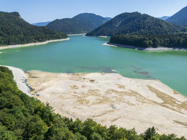 13 August 2026, Bavaria, Vorderriss: Rowing boats are moored on a sandbar along the shore of Lake Sylvenstein, which lies on the border with Tyrol. Photo: Peter Kneffel/dpa