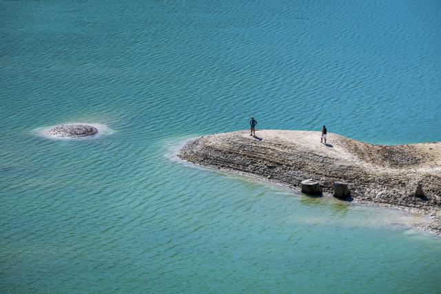 13 August 2026, Bavaria, Vorderriss: Two people out for a walk are standing on the exposed bed of the Sylvenstein Reservoir, which lies on the border with Tyrol. Photo: Peter Kneffel/dpa