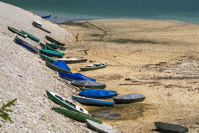 13 August 2026, Bavaria, Vorderriss: Rowing boats are moored on a sandbar along the shore of Lake Sylvenstein, which lies on the border with Tyrol. Photo: Peter Kneffel/dpa