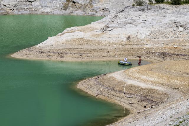 13 August 2026, Bavaria, Vorderriss: People stand at the edge of the Sylvenstein Reservoir, which lies on the border with Tyrol. Photo: Peter Kneffel/dpa