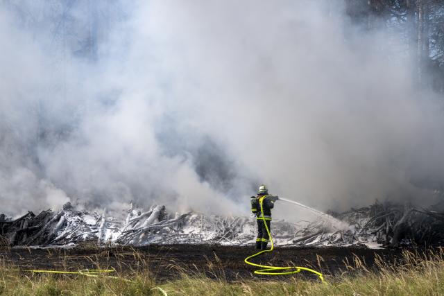 13 August 2026, Bavaria, Brunnthal: A firefighter extinguishes a brush fire in the area between Sauerlach and Hofolding. Photo: Peter Kneffel/dpa