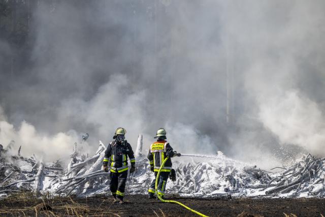 13 August 2026, Bavaria, Brunnthal: Firefighters extinguish a brush fire in the area between Sauerlach and Hofolding. Photo: Peter Kneffel/dpa