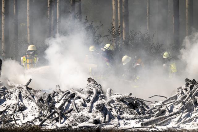 13 August 2026, Bavaria, Brunnthal: Firefighters extinguish a brush fire in the area between Sauerlach and Hofolding. Photo: Peter Kneffel/dpa