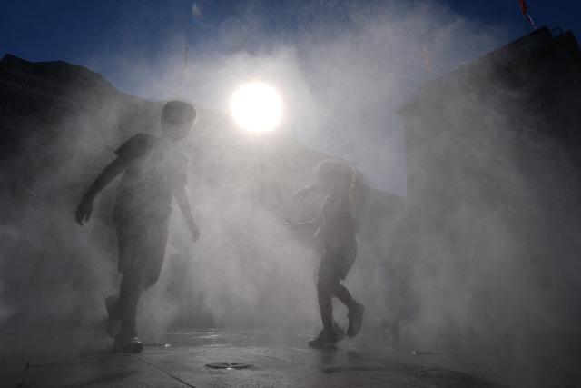13 August 2026, Hamburg: Children are cooling off in a mist of water at Jungfernstieg in the city center. Photo: Marcus Brandt/dpa
