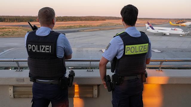 12 August 2026, North Rhine-Westphalia, Cologne: Police officers look out over the Cologne/Bonn Airport grounds. Several drones have been spotted at the airport and have disrupted flight operations. Photo: Alexander Franz/dpa