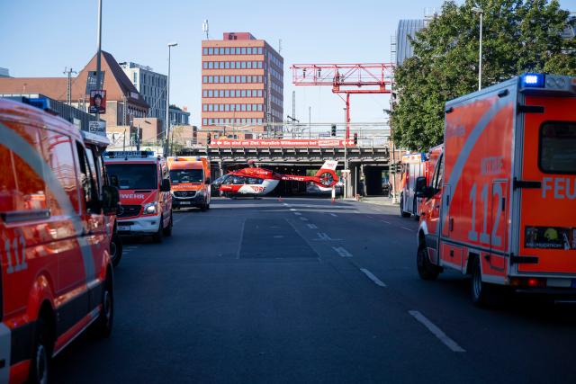 14 August 2026, Berlin: Fire trucks, ambulances, and a rescue helicopter are stationed near a fire as firefighters work in a high-rise building in Friedrichshain. Photo: Christophe Gateau/dpa