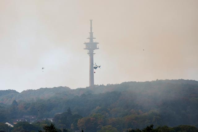 14 August 2026, North Rhine-Westphalia, Hürtgenwald: Federal Police helicopters equipped with external water tanks are in action at a wildfire in the Hürtgenwald. Several hundred hectares of forest are ablaze. Photo: Thomas Banneyer/dpa