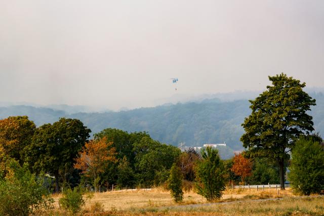 14 August 2026, North Rhine-Westphalia, Hürtgenwald: Federal Police helicopters equipped with external water tanks are on the scene of a forest fire in the Hürtgenwald. Several hundred hectares of forest are ablaze. Photo: Thomas Banneyer/dpa