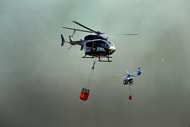 14 August 2026, North Rhine-Westphalia, Hürtgenwald-Großhau: Helicopters are flying in to collect water in external water tanks for use in fighting the forest fire in the Huertgenwald. Several hundred hectares of forest are ablaze. Photo: Federico Gambarini/dpa
