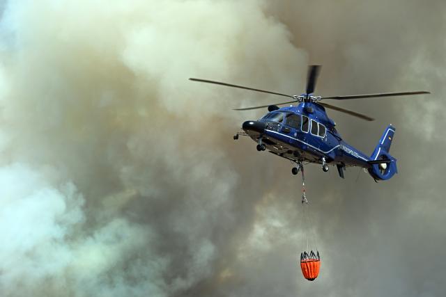 14 August 2026, North Rhine-Westphalia, Huertgenwald-Grosshau: A helicopter is scooping up water into external water tanks to fight the wildfire in the Huertgenwald. Photo: Federico Gambarini/dpa