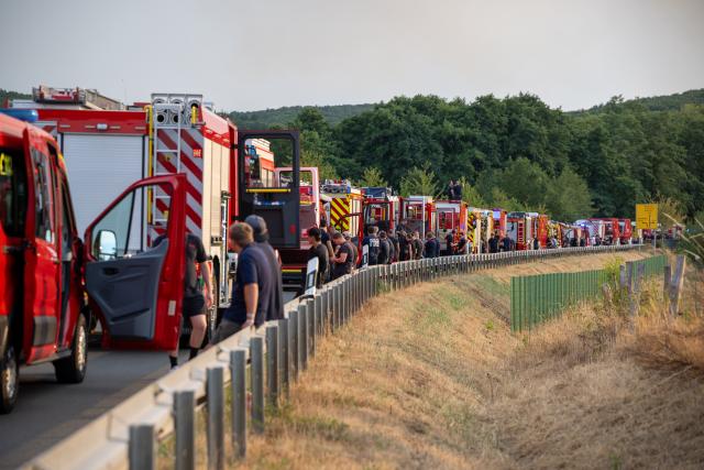 14 August 2026, North Rhine-Westphalia, Huertgenwald-Großhau: Firefighters stand by on the B399 near Huertgenwald-Gey. Photo: Harald Tittel/dpa