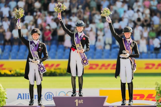 14 August 2026, North Rhine-Westphalia, Aachen: German rider Katharina Hemmer (right) celebrates her bronze medal alongside British gold medallist Charlotte Fry (centre) and Danish silver medallist Cathrine Laudrup-Dufour after the individual Grand Prix Special final at the World Championships. Photo: Rolf Vennenbernd/dpa