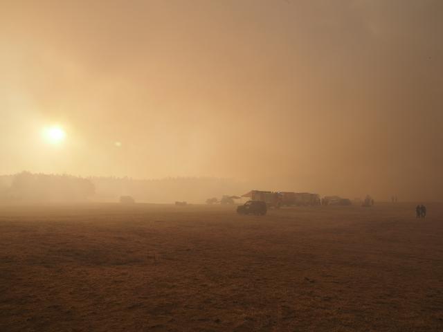 14 August 2026, North Rhine-Westphalia, Huertgenwald: Fire trucks are surrounded by smoke from a forest fire near the hamlet of Grosshau in the municipality of Huertgenwald at a staging area. Photo: Georg Hilgemann/dpa