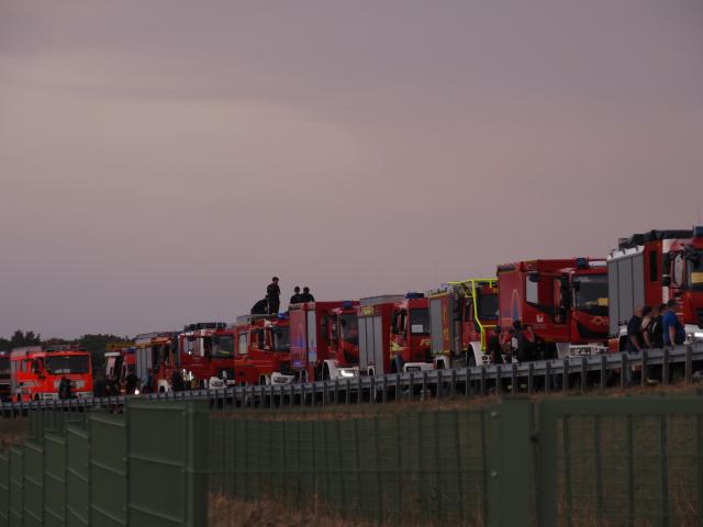 14 August 2026, North Rhine-Westphalia, Huertgenwald: Firefighters wait with their vehicles on the closed Federal Highway 399 near Hürtgenwald-Gey, ready to respond to a forest fire in the municipality of Hürtgenwald. Photo: Georg Hilgemann/dpa