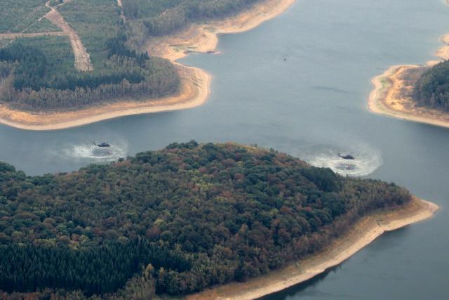 15 August 2026, North Rhine-Westphalia, Hürtgenwald: An aerial view shows helicopters scooping up water to fight the wildfire in the Huertgenwald. Several hundred hectares of forest are ablaze in the Huertgenwald. Photo: Sascha Thelen/dpa