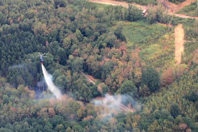 15 August 2026, North Rhine-Westphalia, Hürtgenwald: An aerial footage shows a helicopter fighting a forest fire in the Huertgenwald. Several hundred hectares of forest are ablaze in the Huertgenwald. Photo: Sascha Thelen/dpa