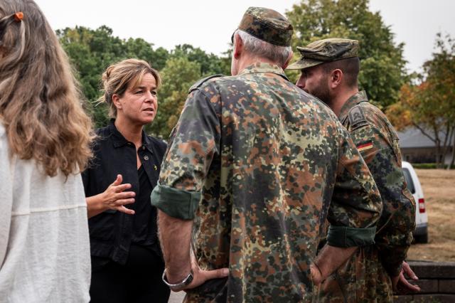 15 August 2026, North Rhine-Westphalia, Huertgenwald: Deputy Minister-President and Minister of Economic Affairs of North Rhine-Westphalia Mona Neubaur talks with German Armed Forces 
(Bundeswehr) soldiers during a visit to the teams fighting the forest fire in the Huertgenwald. Photo: Christian Knieps/dpa