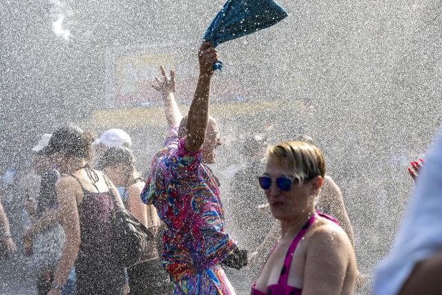 15 August 2026, Berlin: Participants in the "Rave The Planet Parade 2026" demonstration cool off under the mist from a police water cannon. Photo: Christophe Gateau/dpa