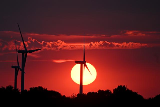 15 August 2026, North Rhine-Westphalia, Erp: The setting sun paints the sky red behind the wind turbines. Photo: Federico Gambarini/dpa