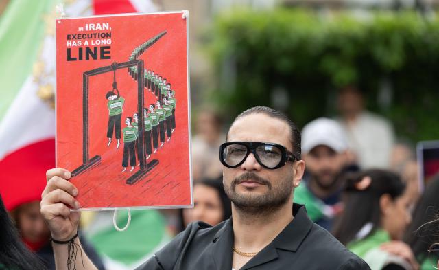 FILED - 16 May 2026, Hesse, Frankfurt_Main: FILE PHOTO - A man holds a sign that reads, "In Iran, Execution has a long line", during a demonstration at Rathenauplatz in support of the Iranian opposition politician and son of the Shah Pahlavi. Photo: Boris Roessler/dpa